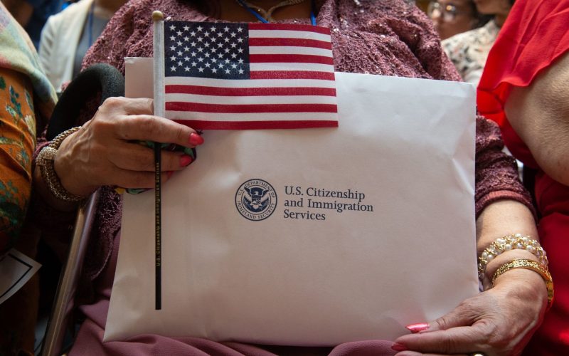 A woman holds the flag and her paperwork as the US Citizenship and Immigration Services welcomes 200 new citizens from 50 countries during a ceremony in honor of Independence Day at the New York Public Library on July 3, 2018 in New York. (Photo by Bryan R. Smith / AFP)        (Photo credit should read BRYAN R. SMITH/AFP via Getty Images)
